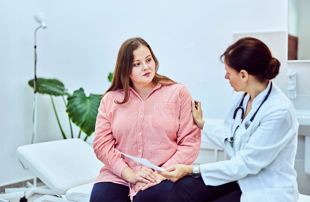 An overweight patient speaks to a doctor