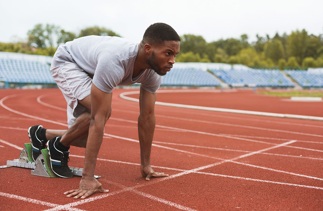 man crouched at the starting line of a track