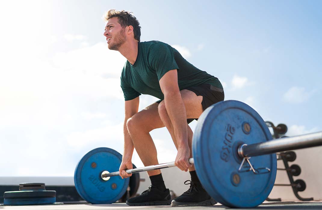 A male athlete practices weightlifting outdoors