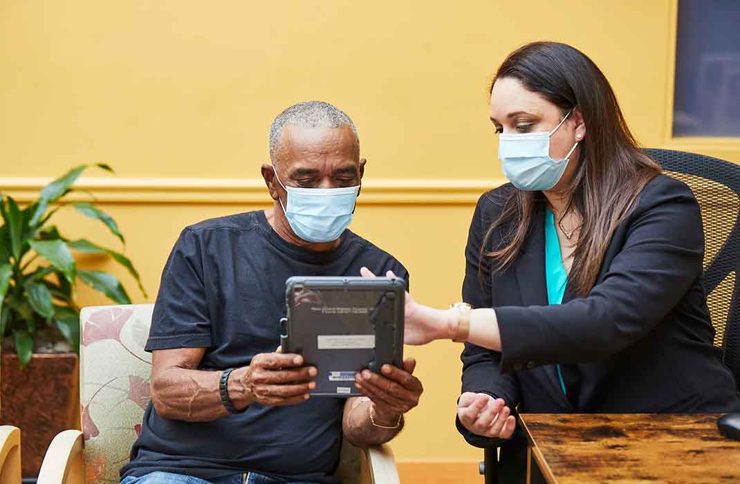 Healthcare professional assisting patient in their use of a tablet