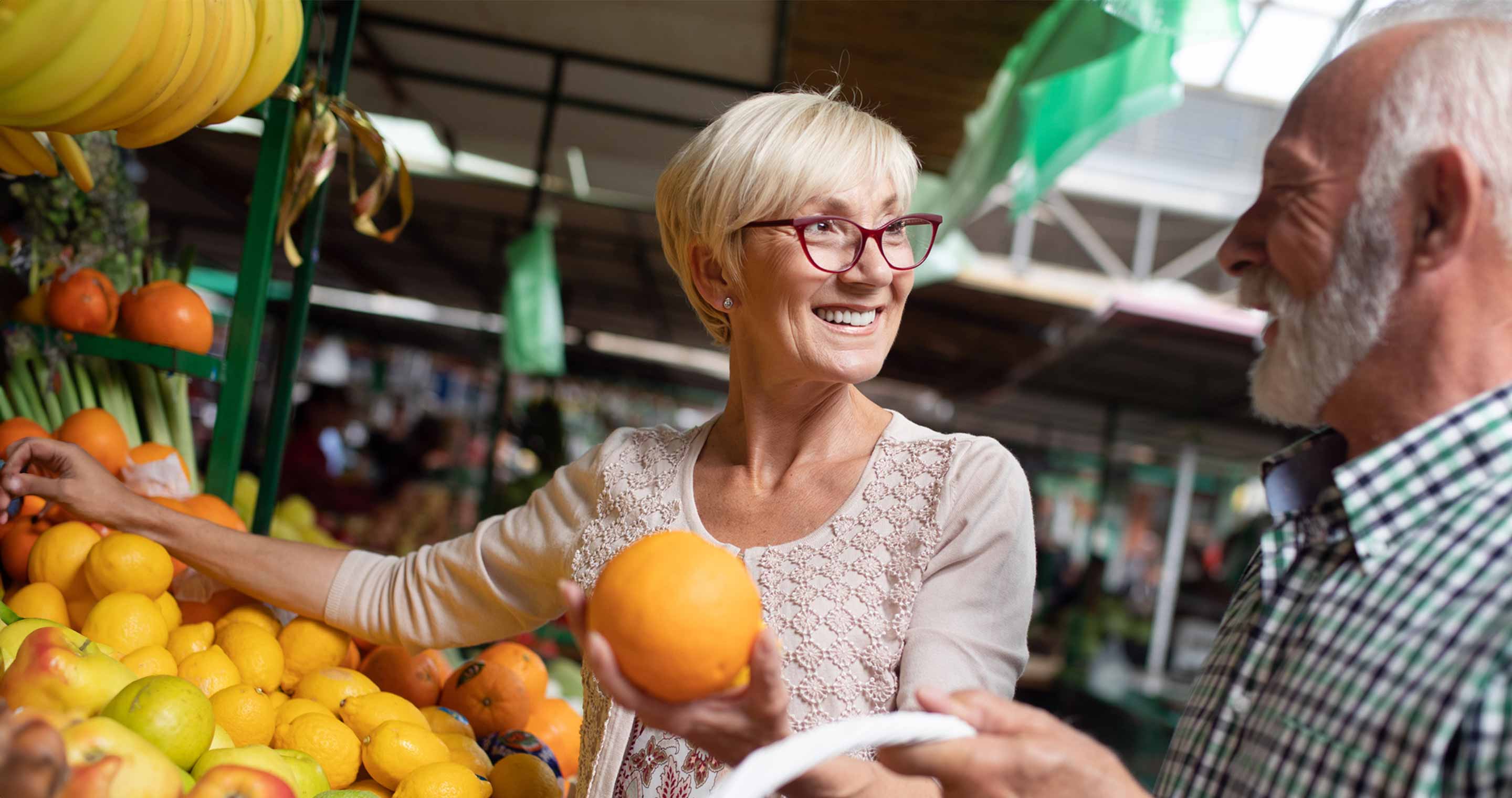 man and woman smiling while picking oranges at grocery store