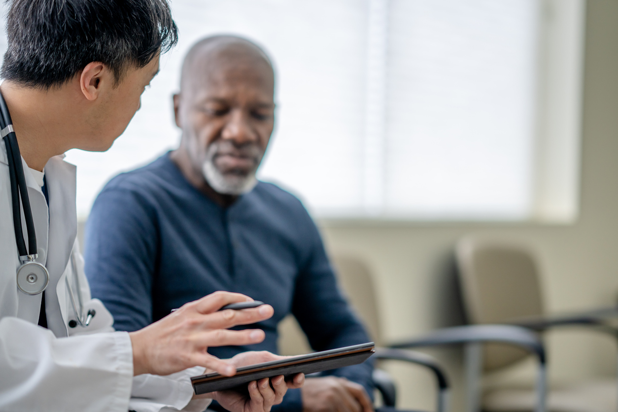 Senior man talking with doctor and looking at tablet