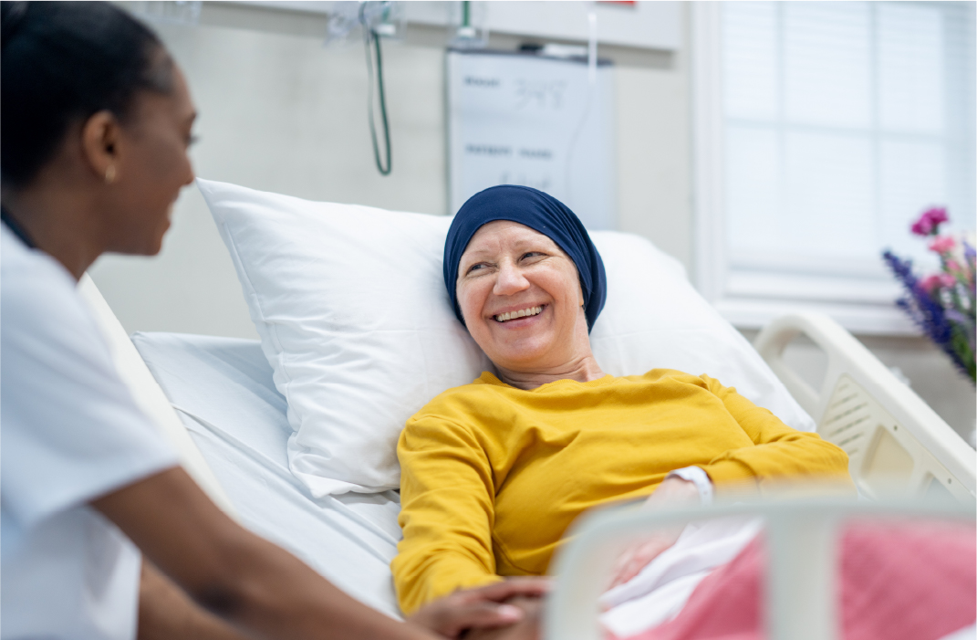 A woman in a hospital bed, smiling at nurse