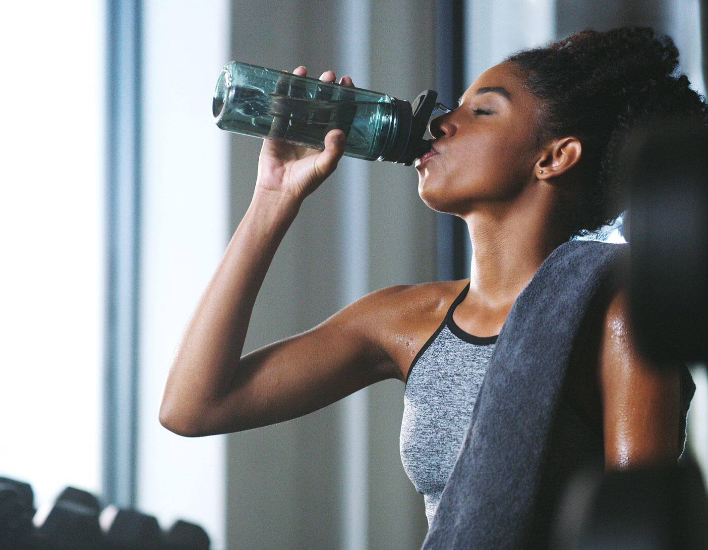 woman drinking water from bottle in gym
