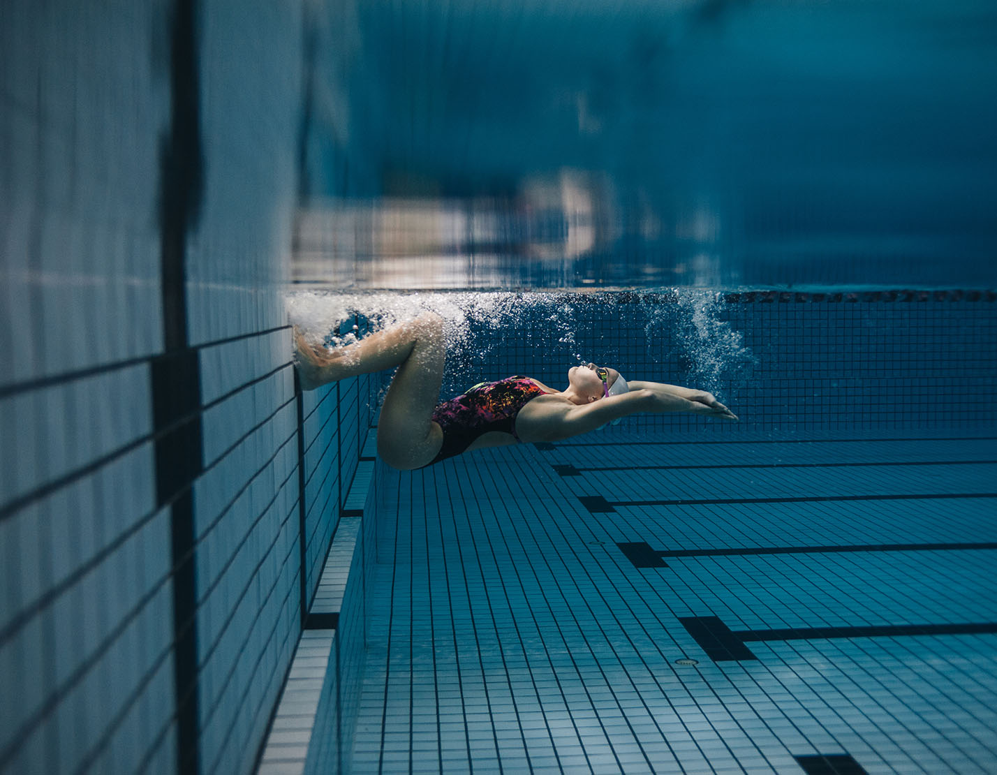 female swimmer kicking off from wall of pool