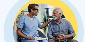 A smiling doctor talks with an older male patient.