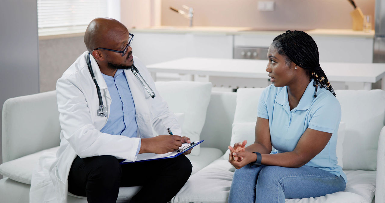 A health care provider speaks with a worried African-American woman.