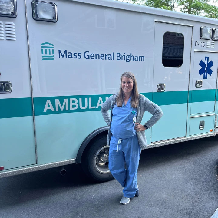 female medical provider in scrubs standing beside a Mass General Brigham ambulance