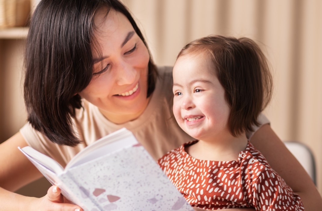 A mother reading with her daughter with Down syndrome.