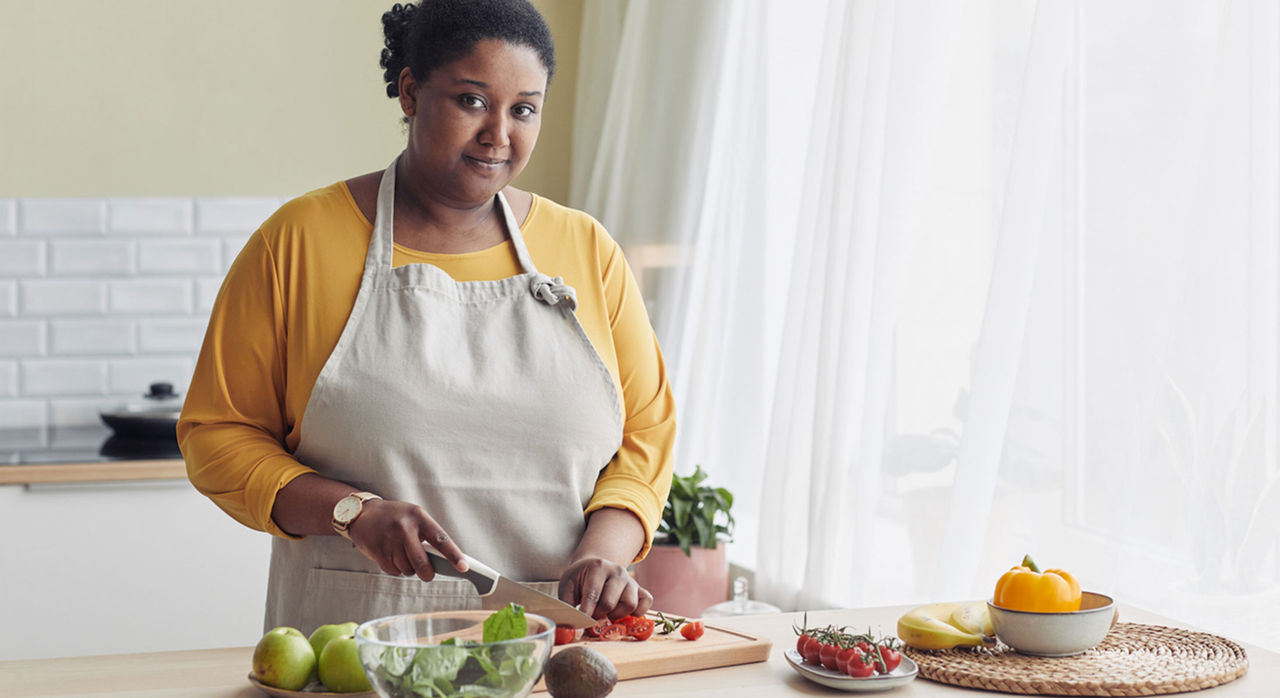 Woman preps meal low in dietary fat to reduce risk of heart disease.