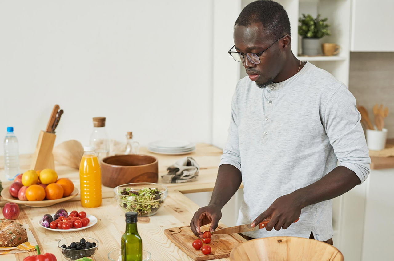 Food Is Medicine A young man prepares ingredients for a meal with fresh produce in his kitchen