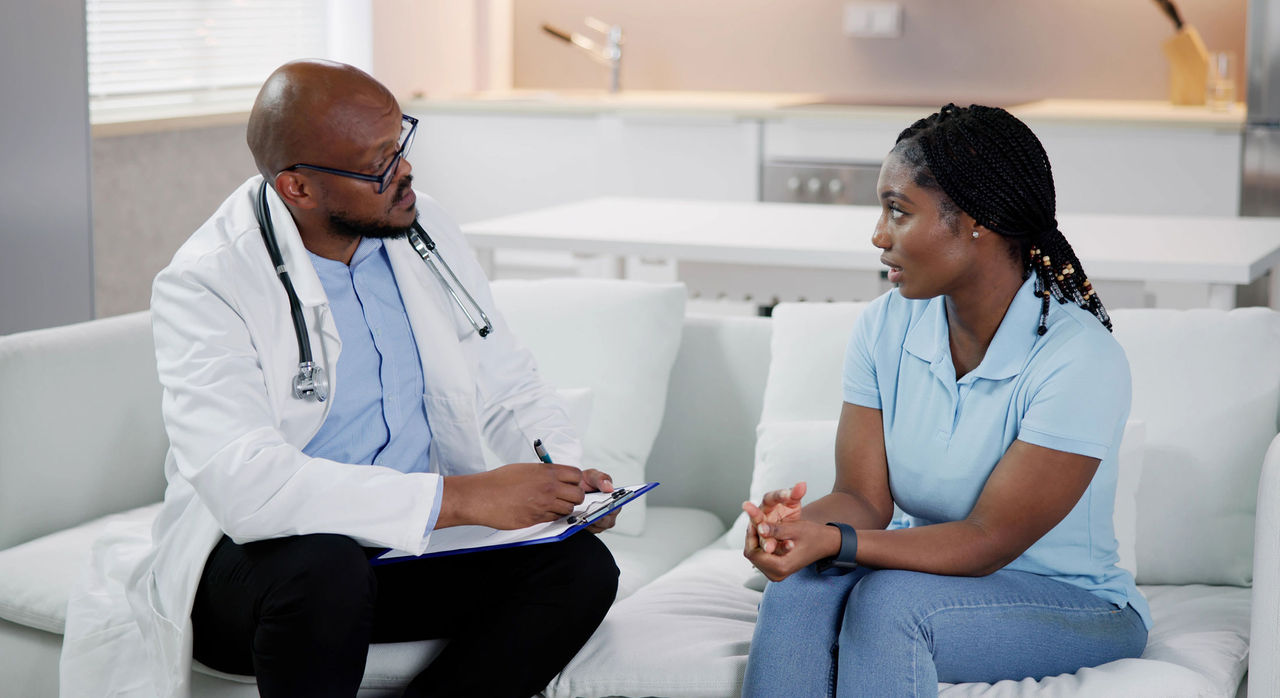 A health care provider speaks with a worried African-American woman.