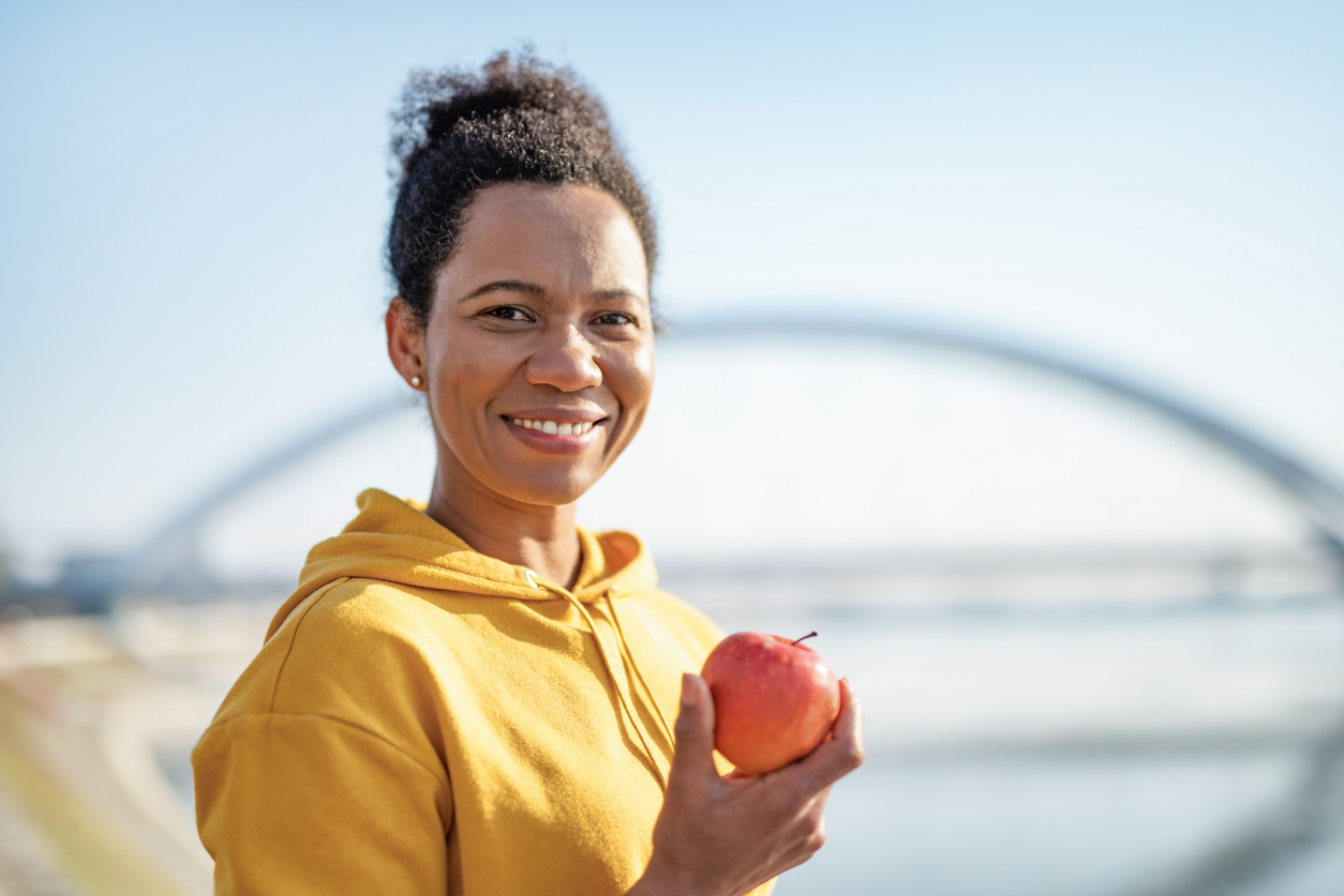1223055039 Sporty African American woman eating an Apple outdoors, after exercise.