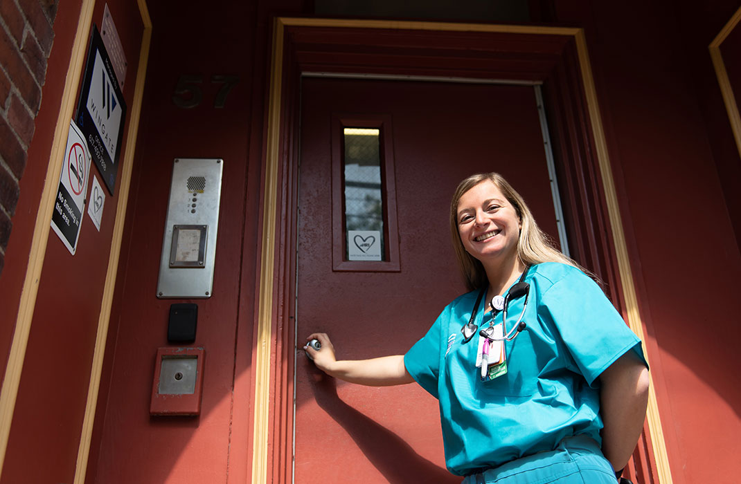 A Home Hospital clinician stands at the door of a patient’s home.