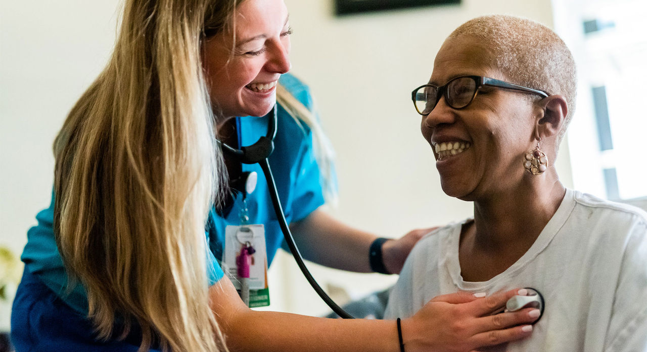 A health care provider listens to a patient’s heart with a stethoscope.