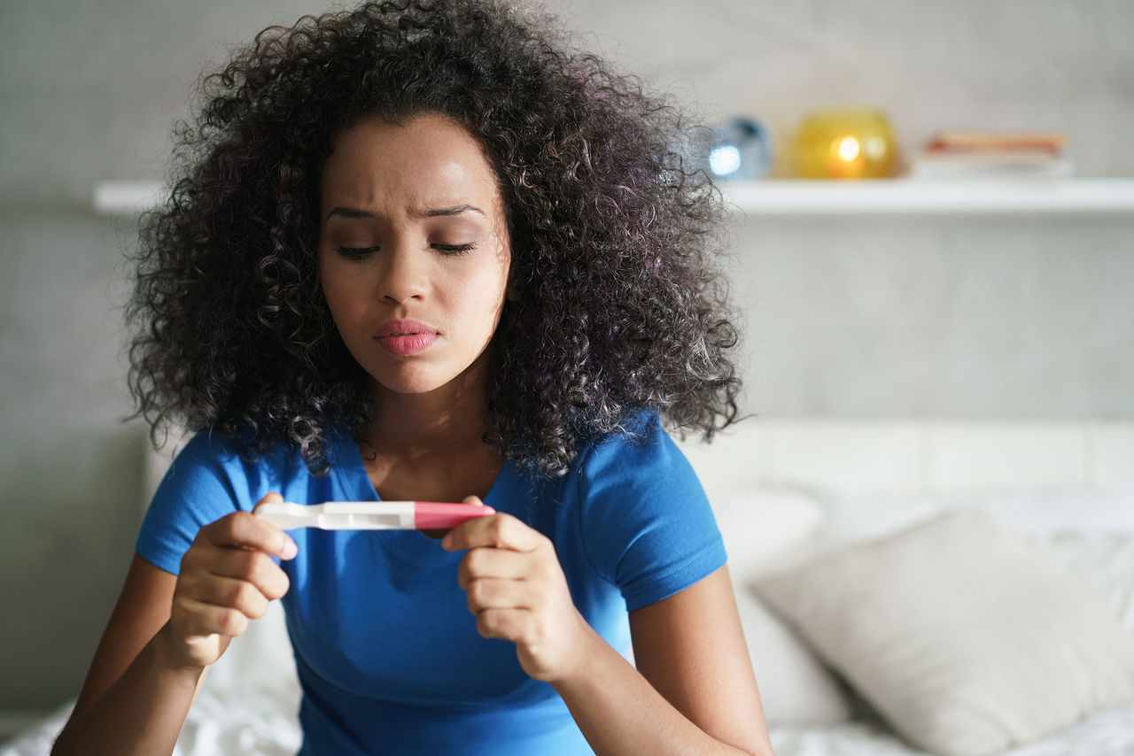 A worried woman looks at a pregnancy test.