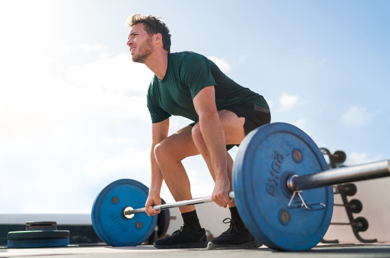 A male athlete practices weightlifting outdoors