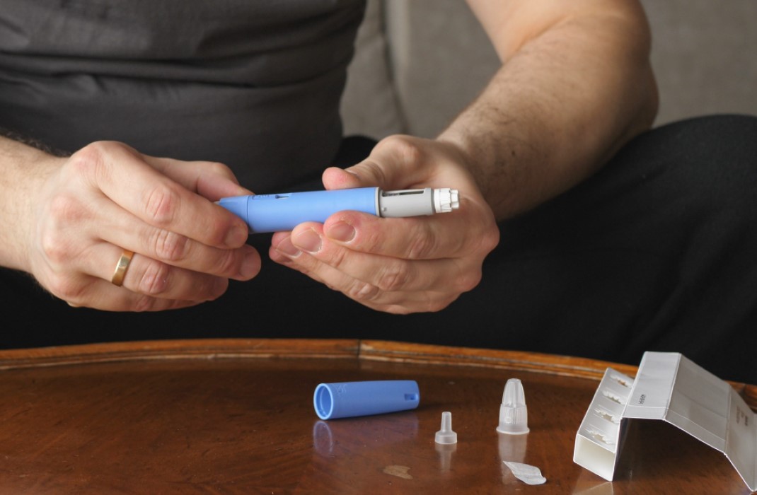 A man prepares to take an injection of weight loss medication