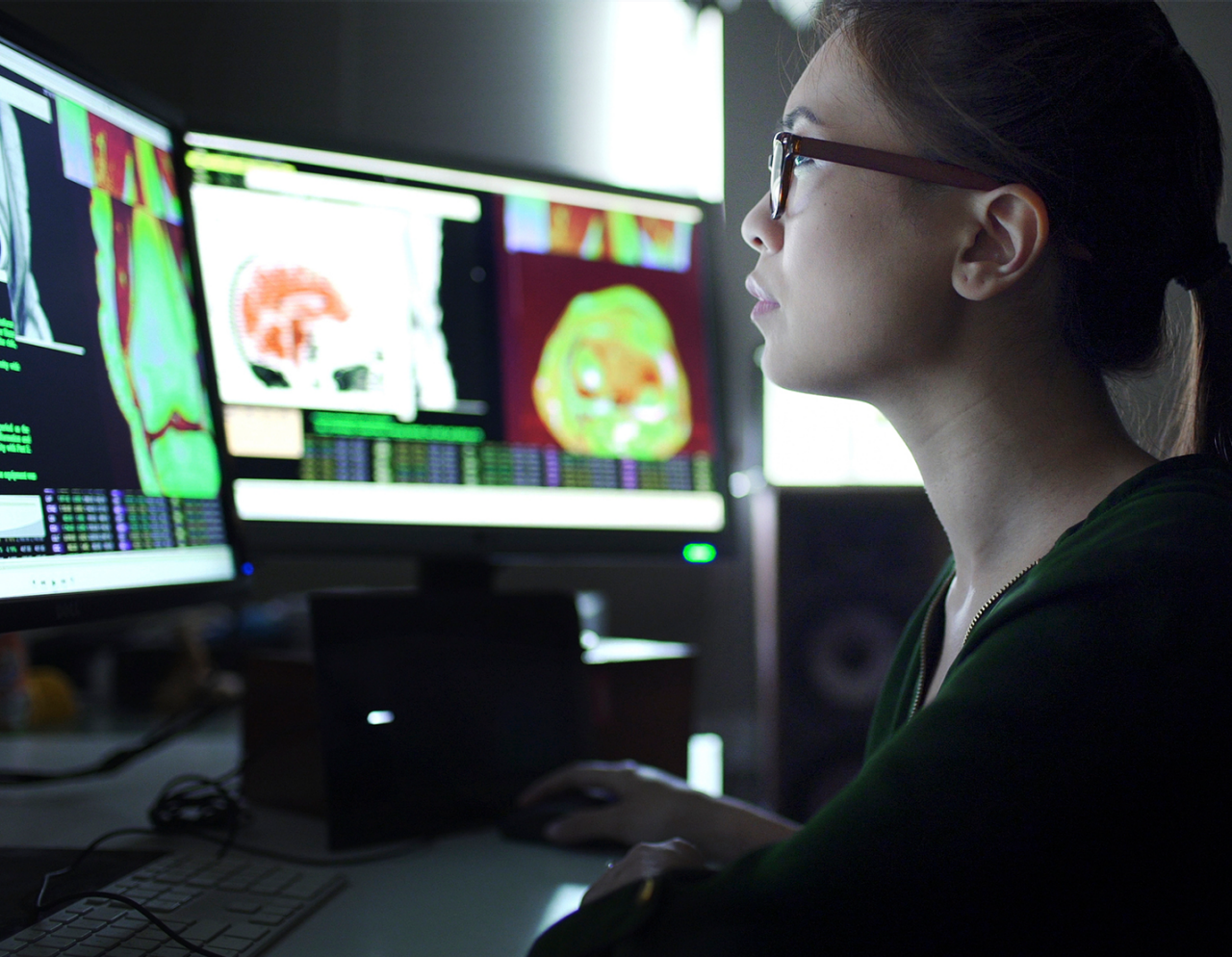 woman reviewing data and images on two sets of monitors  