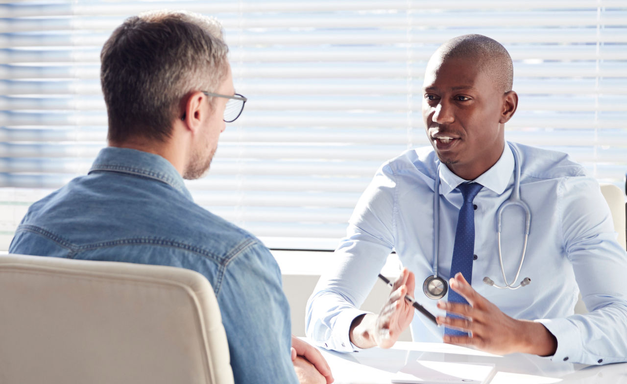 A make doctor having a conversation with a male patient in an office.