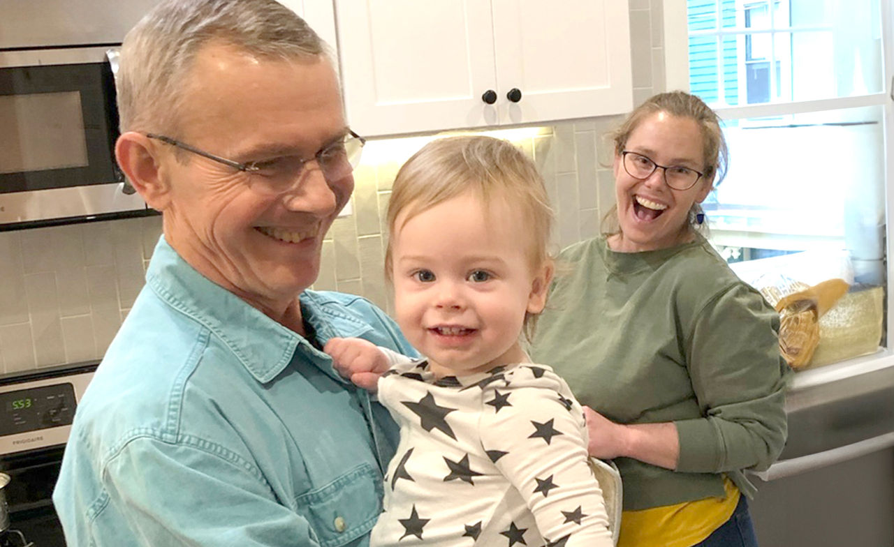 Martin, baby Alden, and Lucy Orloski smiling in the kitchen