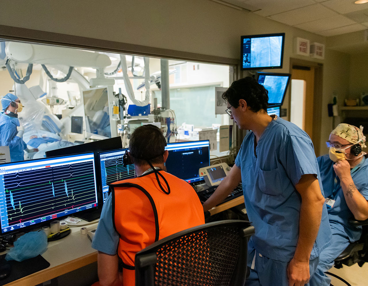 members of the heart care team outside operating room monitoring patient during surgery