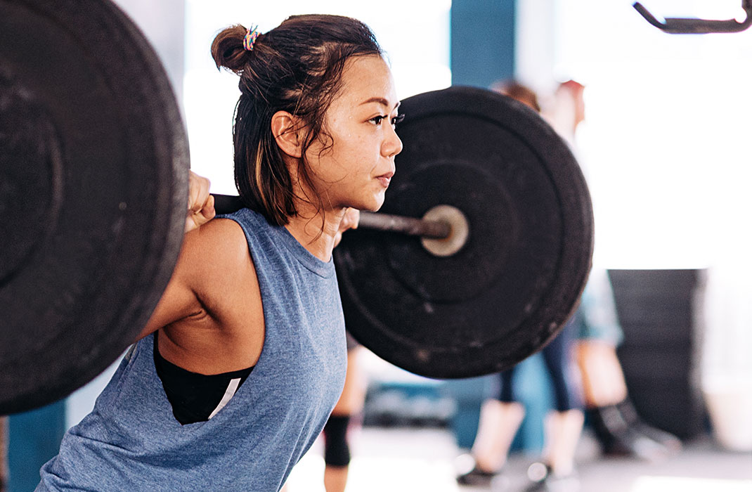 woman squatting with barbell on her shoulders in gym